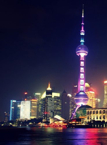 Vibrant nighttime view of Shanghai's iconic skyline featuring the illuminated Oriental Pearl Tower.