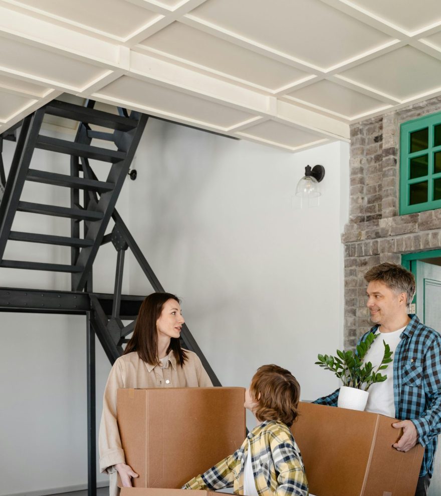 A happy family carrying boxes inside their new home, capturing the joy of moving in.