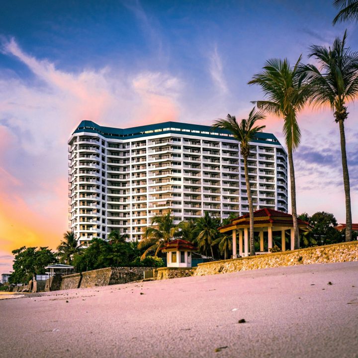 Stunning view of a beachfront resort with palm trees silhouetted against a vibrant sunset.